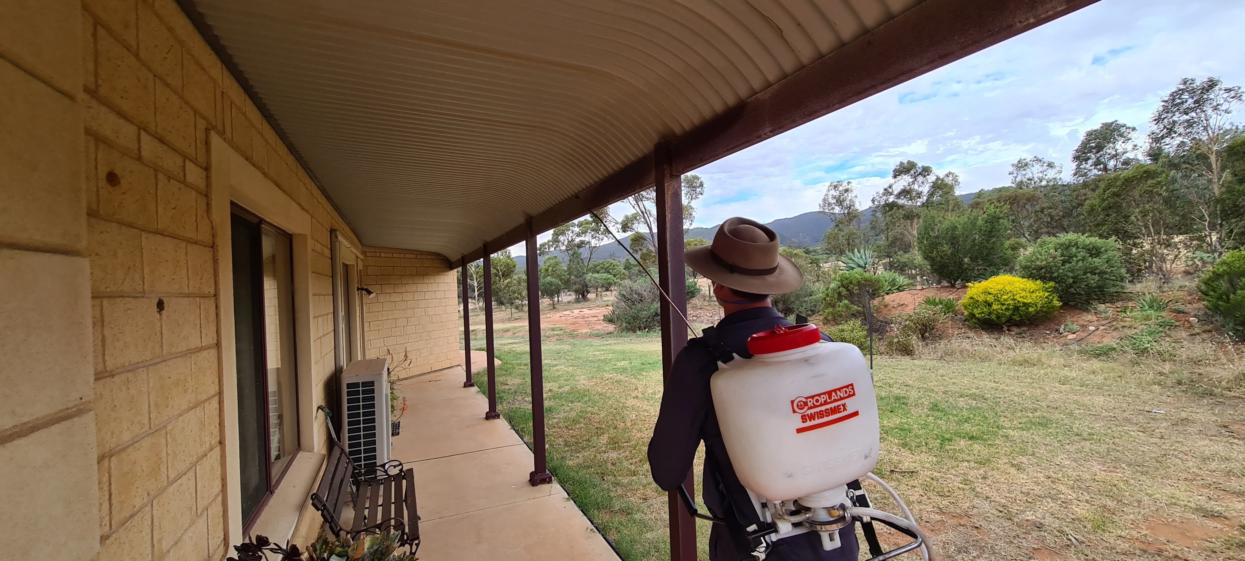 Adam from Aussie Mozzie spraying around a verandah on a rural property